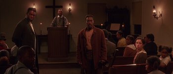 Movie still from “Rosewood” (1997), directed by John Singleton – A man standing in front of an audience in a church; Medium shot, Low angle