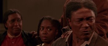 Movie still from “Rosewood” (1997), directed by John Singleton – A group of people that are sitting in a room together; Close Up shot, Over the shoulder angle