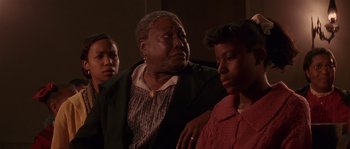 Movie still from “Rosewood” (1997), directed by John Singleton – A group of people sitting next to each other in a room; Close Up shot, Low angle