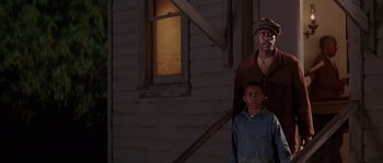 Movie still from “Rosewood” (1997), directed by John Singleton – A man and a boy standing in front of a building; Medium shot, Low angle