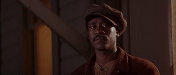 Movie still from “Rosewood” (1997), directed by John Singleton – A man wearing a hat and a brown jacket; Close Up shot, Low angle