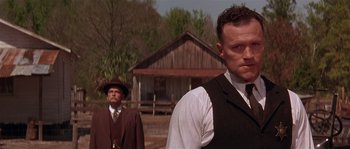 Movie still from “Rosewood” (1997), directed by John Singleton – A man in a suit and tie standing next to another man in a suit and tie; Close Up shot, Low angle