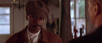 Movie still from “Rosewood” (1997), directed by John Singleton – A man wearing a hat and a brown jacket; Close Up shot, Low angle