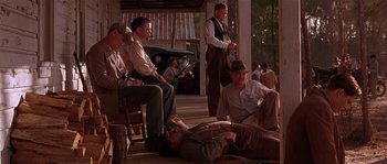 Movie still from “Rosewood” (1997), directed by John Singleton – A group of men sitting and standing on a porch; Wide shot, Low angle