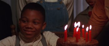 Movie still from “Rosewood” (1997), directed by John Singleton – A young boy sitting in front of a birthday cake; Close Up shot, High angle