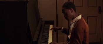 Movie still from “Rosewood” (1997), directed by John Singleton – A man is playing the piano in a room; Close Up shot, High angle