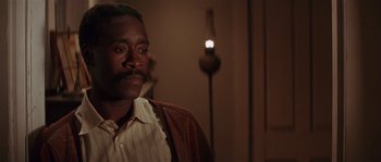 Movie still from “Rosewood” (1997), directed by John Singleton – A man with a beard and mustache is sitting in front of a lamp; Close Up shot, Over the shoulder angle