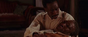 Movie still from “Rosewood” (1997), directed by John Singleton – An older man reading a book at a table; Close Up shot, High angle