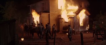 Movie still from “Rosewood” (1997), directed by John Singleton – A group of men are standing in front of a burning building; Wide shot, High angle