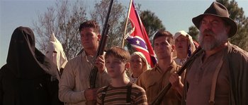 Movie still from “Rosewood” (1997), directed by John Singleton – A group of people standing next to each other holding guns; Medium shot, Low angle