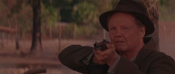 Movie still from “Rosewood” (1997), directed by John Singleton – An older man holding a gun while wearing a hat; Close Up shot, Over the shoulder angle