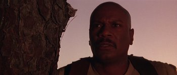 Movie still from “Rosewood” (1997), directed by John Singleton – A man with a beard is standing next to a tree; Close Up shot, Low angle
