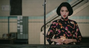 Movie still from “Rouge” (1987), directed by Stanley Kwan – A woman standing in front of a mirror holding a purse; Medium shot, Over the shoulder angle