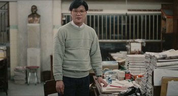Movie still from “Rouge” (1987), directed by Stanley Kwan – A man standing in front of a table full of papers; Medium shot, Low angle