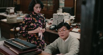 Movie still from “Rouge” (1987), directed by Stanley Kwan – A man and a woman sitting at a computer desk in an office; Medium shot, High angle