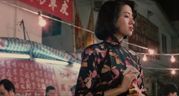 Movie still from “Rouge” (1987), directed by Stanley Kwan – A woman in a black and pink dress standing in a market; Medium shot, Over the shoulder angle
