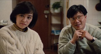 Movie still from “Rouge” (1987), directed by Stanley Kwan – A man and a woman sitting next to each other in a room; Medium shot, High angle