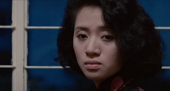 Movie still from “Rouge” (1987), directed by Stanley Kwan – A woman's face in front of a blue wall; Close Up shot, Over the shoulder angle