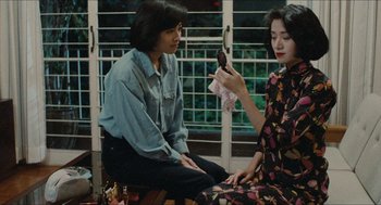 Movie still from “Rouge” (1987), directed by Stanley Kwan – Two young women sitting on a bench looking at a cell phone; Medium shot, High angle