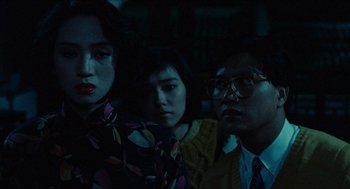 Movie still from “Rouge” (1987), directed by Stanley Kwan – A group of people standing next to each other in a dark room; Medium shot, Over the shoulder angle