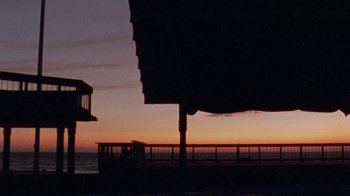 Movie still from “Ruby in Paradise” (1993), directed by Victor Nunez – A person riding a bike on top of a pier; Extreme Wide shot, Low angle