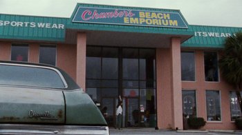 Movie still from “Ruby in Paradise” (1993), directed by Victor Nunez – A woman standing outside of a store with a car parked in front of it; Wide shot, Low angle