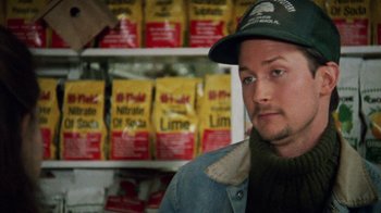Movie still from “Ruby in Paradise” (1993), directed by Victor Nunez – A man wearing a hat standing in front of a shelf of food; Close Up shot, Over the shoulder angle