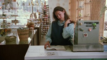 Movie still from “Ruby in Paradise” (1993), directed by Victor Nunez – A woman standing at a counter reading a book; Medium shot, Over the shoulder angle