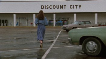 Movie still from “Ruby in Paradise” (1993), directed by Victor Nunez – A woman walking in a parking lot in the rain; Wide shot, High angle