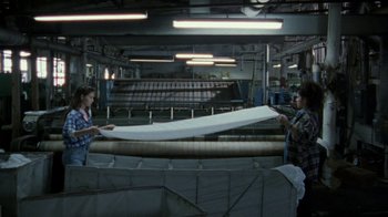 Movie still from “Ruby in Paradise” (1993), directed by Victor Nunez – Two people are working in a factory with a sheet of paper; Wide shot, High angle