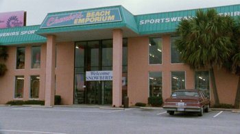Movie still from “Ruby in Paradise” (1993), directed by Victor Nunez – A car parked in front of a sports wear store; Extreme Wide shot, High angle