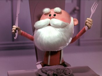 Movie still from “Rudolph the Red-Nosed Reindeer” (1964), directed by Larry Roemer – A cartoon character is holding a knife in one hand and an arm in the other; Medium shot, Low angle