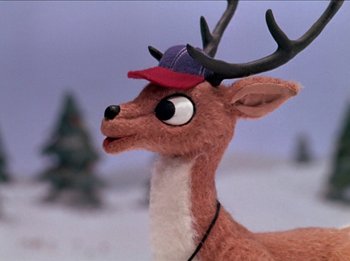 Movie still from “Rudolph the Red-Nosed Reindeer” (1964), directed by Larry Roemer – A stuffed deer wearing a baseball cap in the snow; Close Up shot, Low angle