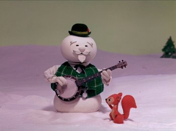 Movie still from “Rudolph the Red-Nosed Reindeer” (1964), directed by Larry Roemer – A snowman with a hat and a banjo next to a red squirrel; Medium shot, Low angle
