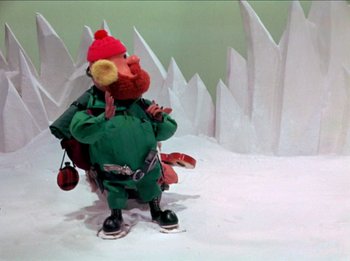 Movie still from “Rudolph the Red-Nosed Reindeer” (1964), directed by Larry Roemer – A stuffed animal in the shape of an elf with a red hat; Wide shot, Low angle