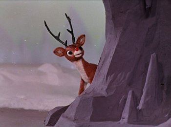 Movie still from “Rudolph the Red-Nosed Reindeer” (1964), directed by Larry Roemer – A deer with a long antler standing on a rock cliff; Medium shot, Low angle