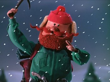 Movie still from “Rudolph the Red-Nosed Reindeer” (1964), directed by Larry Roemer – A gnome holding a shovel in the snow; Medium shot, Low angle