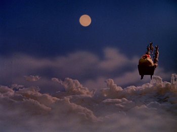Movie still from “Rudolph the Red-Nosed Reindeer” (1964), directed by Larry Roemer – A person flying a kite in the sky with the moon in the background; Extreme Wide shot, High angle