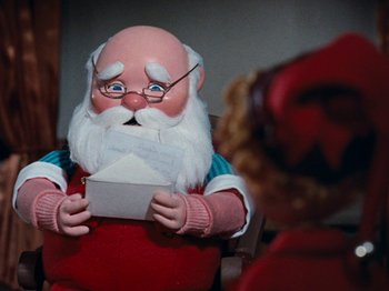 Movie still from “Rudolph's Shiny New Year” (1976), directed by Jules Bass – A santa claus doll holding a letter in his hands; Close Up shot, Low angle