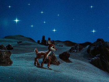Movie still from “Rudolph's Shiny New Year” (1976), directed by Jules Bass – A toy deer standing on top of a sandy beach; Extreme Wide shot, Low angle