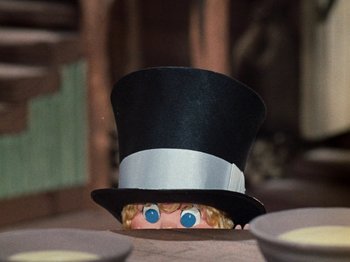 Movie still from “Rudolph's Shiny New Year” (1976), directed by Jules Bass – A doll's head wearing a black top hat; Medium shot, Over the shoulder angle