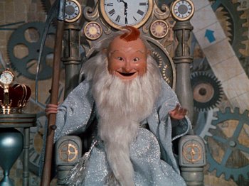 Movie still from “Rudolph's Shiny New Year” (1976), directed by Jules Bass – A doll is sitting in a chair with a beard; Medium shot, Low angle