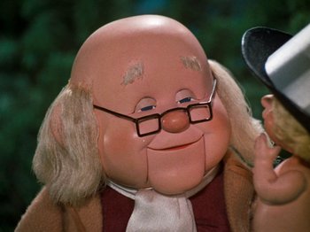 Movie still from “Rudolph's Shiny New Year” (1976), directed by Jules Bass – The face of a doll wearing glasses; Close Up shot, Over the shoulder angle