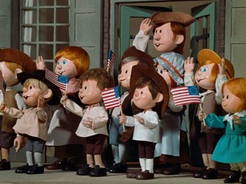 Movie still from “Rudolph's Shiny New Year” (1976), directed by Jules Bass – A group of people standing next to each other holding american flags; Medium shot, Low angle
