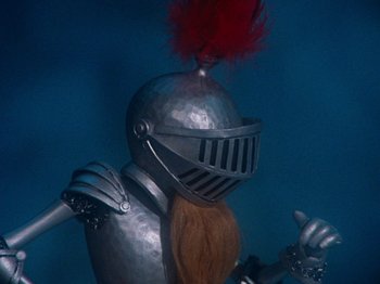 Movie still from “Rudolph's Shiny New Year” (1976), directed by Jules Bass – A metal suit of armor with a red wig; Close Up shot, High angle