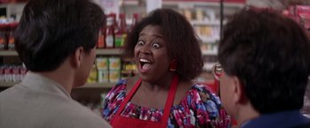 Movie still from “Rumble in the Bronx” (1995), directed by Stanley Tong – A woman in a red and blue apron is making a funny face; Close Up shot, Over the shoulder angle