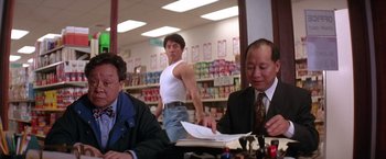 Movie still from “Rumble in the Bronx” (1995), directed by Stanley Tong – A man standing in front of two other men in a grocery store; Medium shot, Low angle