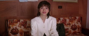 Movie still from “Rumble in the Bronx” (1995), directed by Stanley Tong – A woman wearing a white jacket sitting on a couch; Close Up shot, High angle