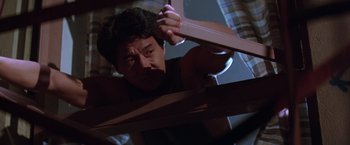 Movie still from “Rumble in the Bronx” (1995), directed by Stanley Tong – A man is holding a piece of wood up to his face; Medium shot, Low angle