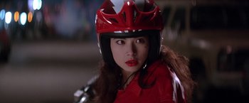 Movie still from “Rumble in the Bronx” (1995), directed by Stanley Tong – A woman wearing a red motorcycle helmet and a red jacket; Close Up shot, Low angle
